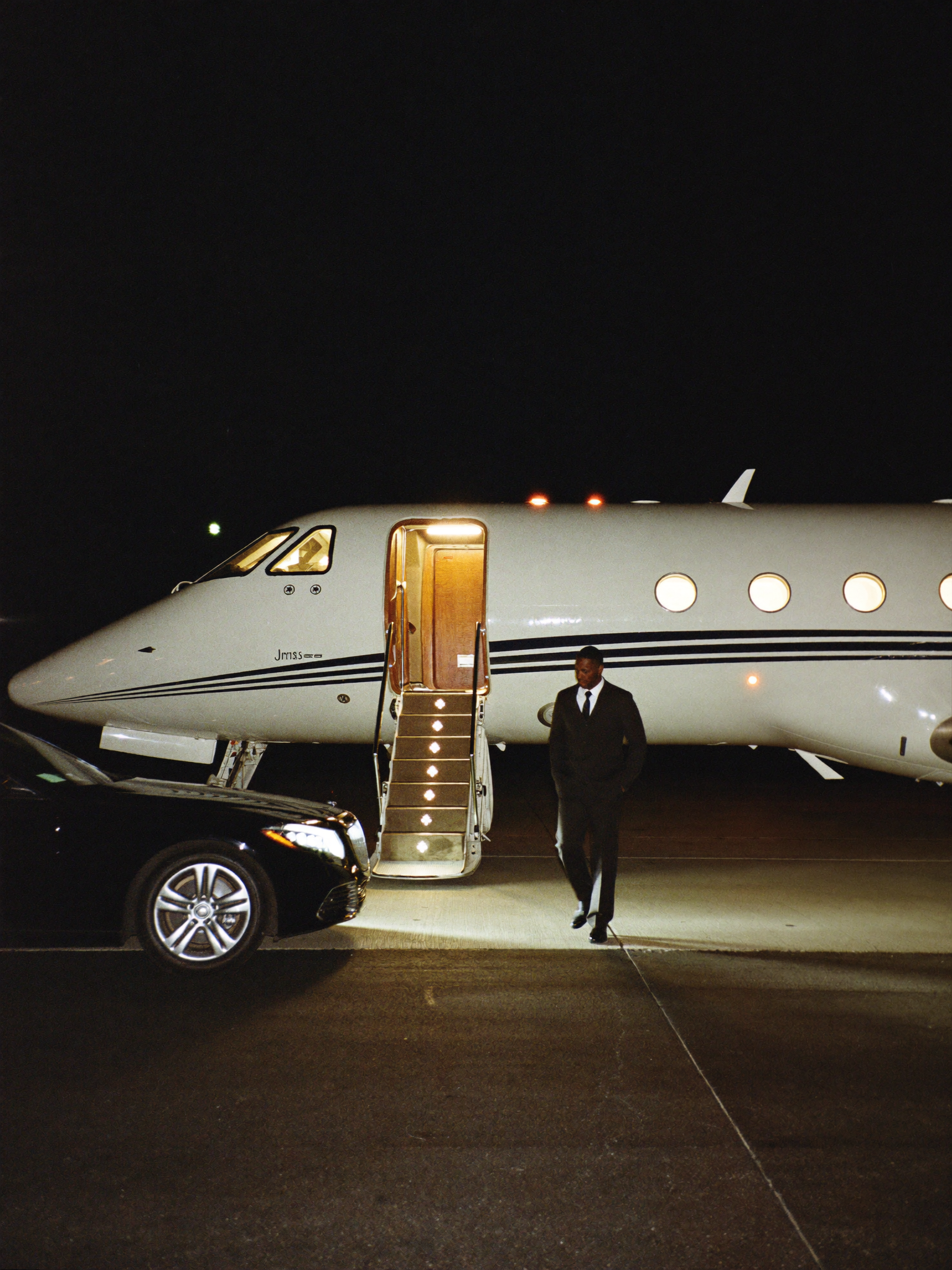 A private jet on the apron at night with a car waiting at the airstair