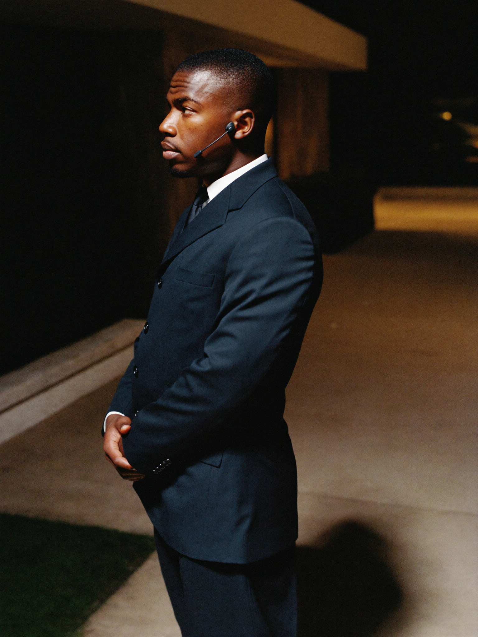A close-protection officer at the edge of a driveway at night